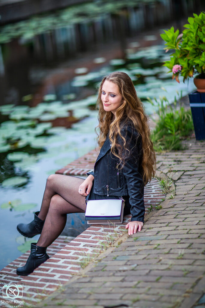 Female model Marina Krivonossova closes her eyes and smiles during a fashion photoshoot by a canal in the Netherlands.