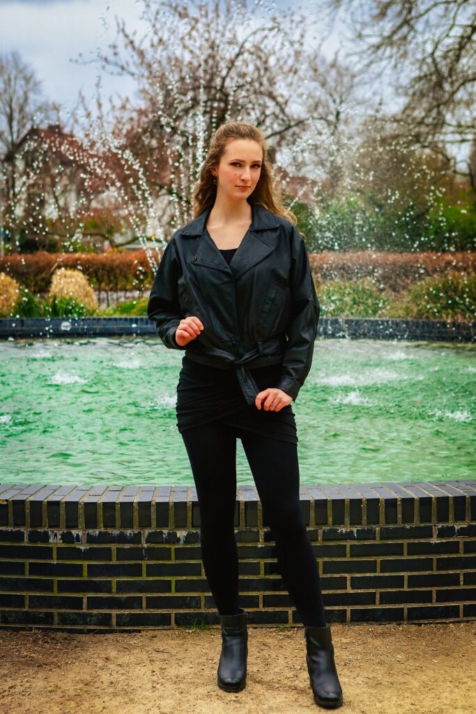 Female model Marina Krivonossova holds on to her jacket as she strikes a pose in front of a fountain. Marina is modeling a hand-painted leather jacket during a city photoshoot in the Netherlands.