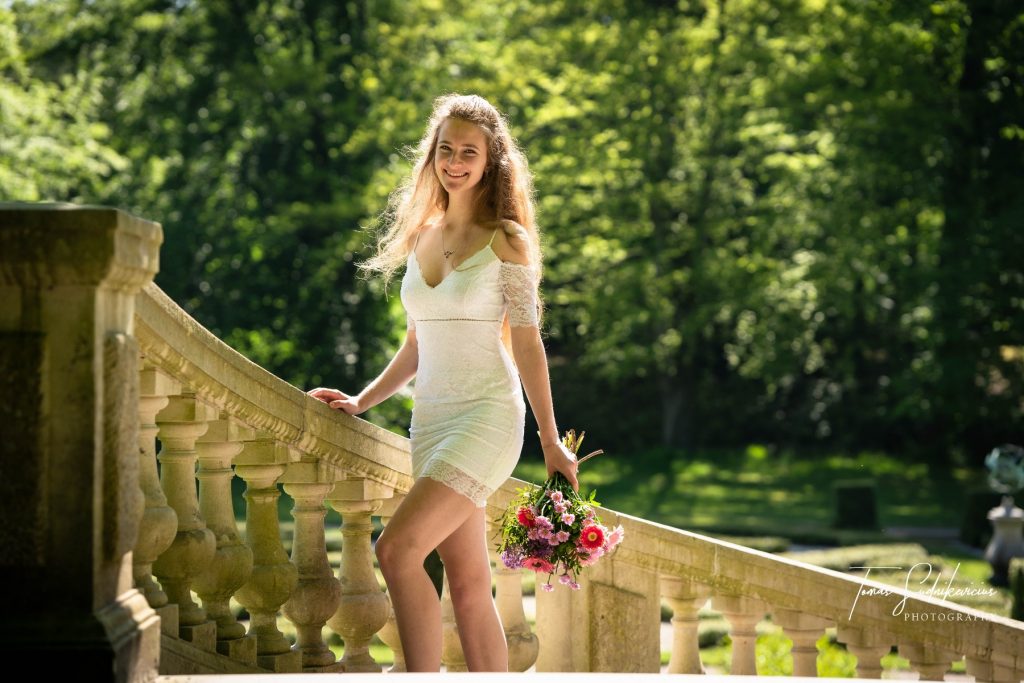 Female model photoshoot image. She smiles at the camera during a wedding photoshoot. She looks at the camera and smiles as she begins walking up the stairs.