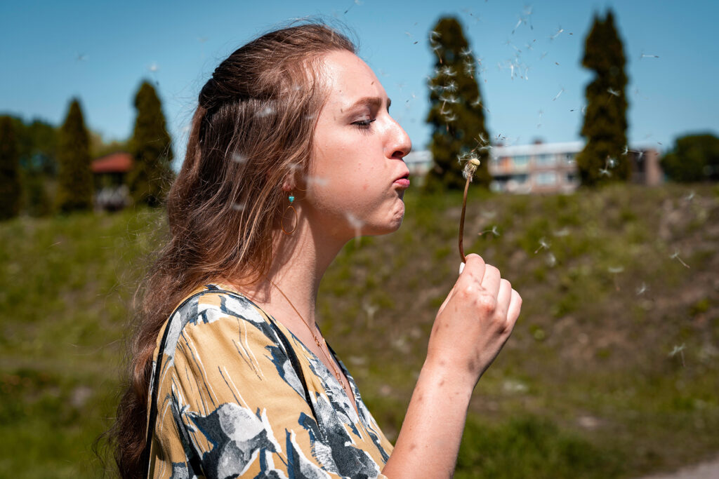 Female model Marina Krivonossova takes a picture with a dandelion during a photoshoot.