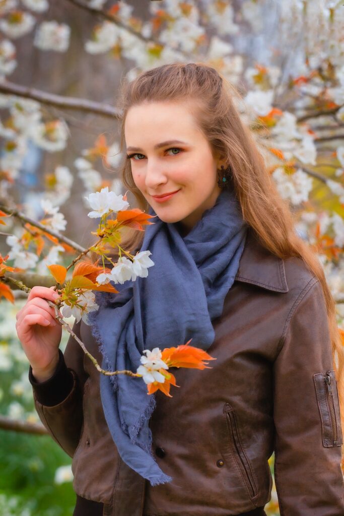 Female model Marina Krivonossova holds on to a tree branch with flowers during a fashion photoshoot in a city in the Netherlands.