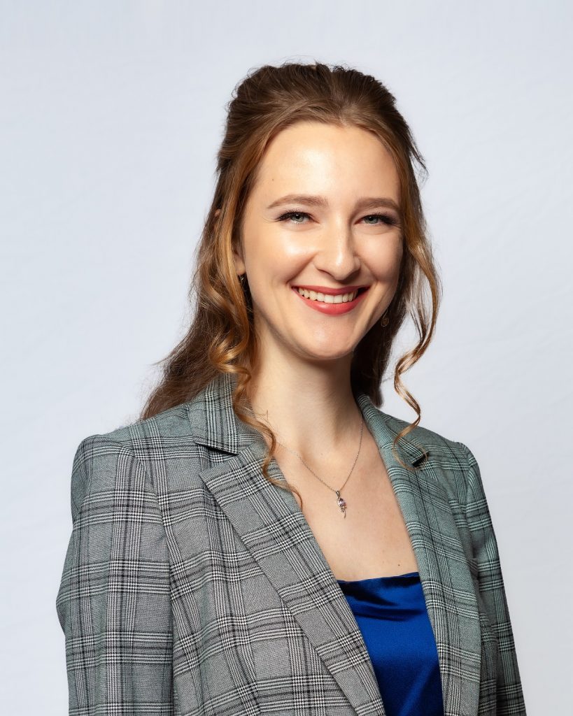 Female model photoshoot image. She smiles at the camera during a business-themed studio photoshoot.