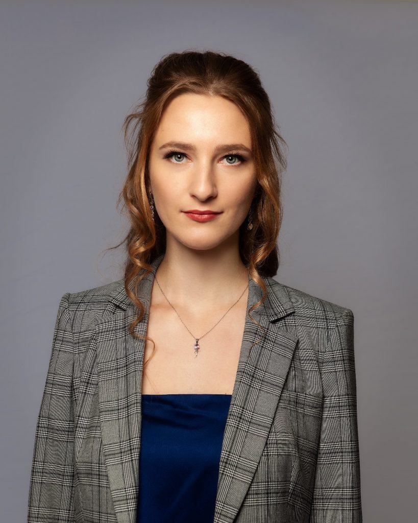 Female model photoshoot image. She looks directly at the camera during a business-themed studio photoshoot.